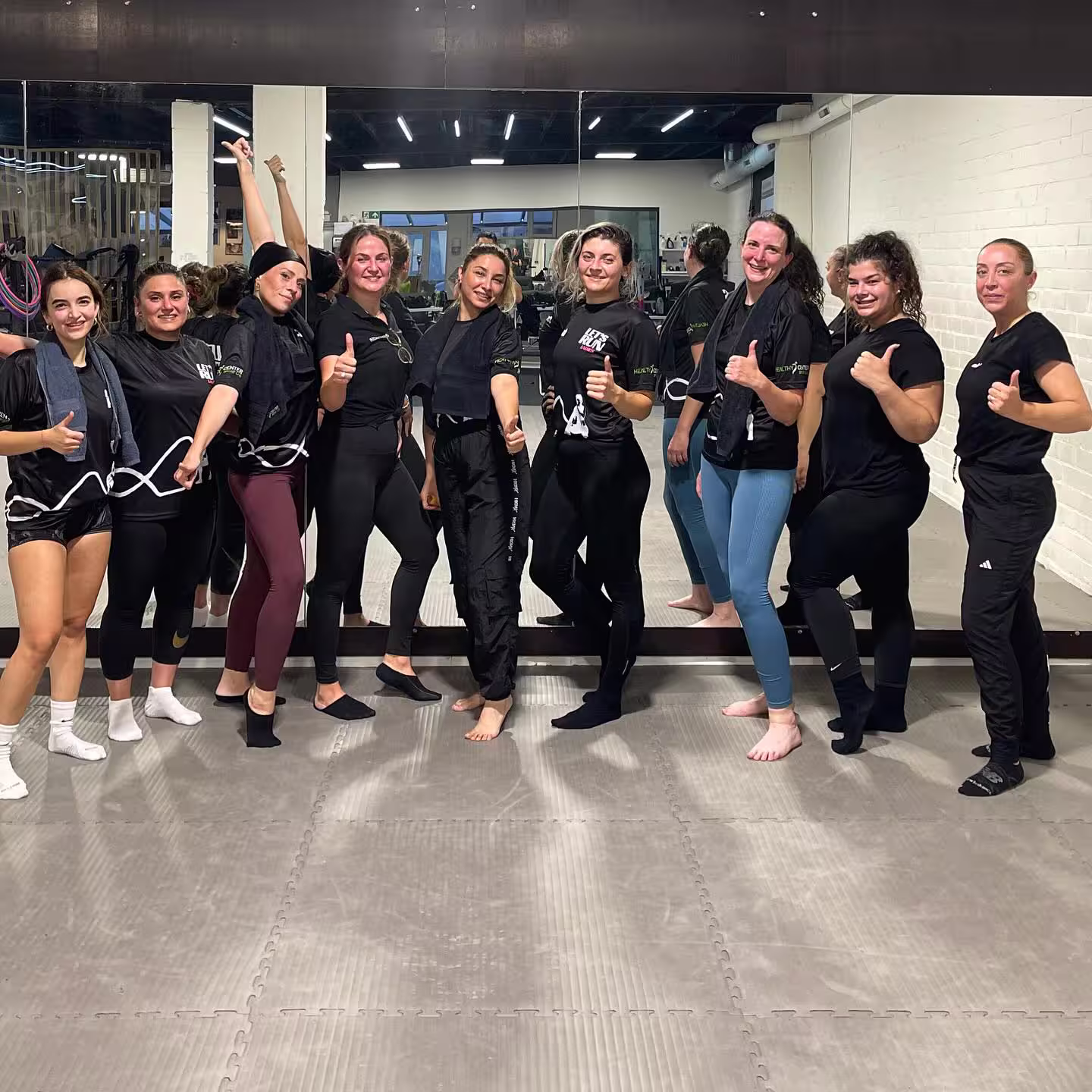 Groep vrouwen doet energieke full body cardio fitness les in moderne sportzaal, lachend en gemotiveerd